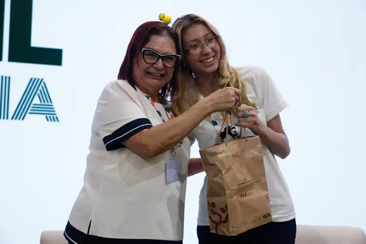 Belém (PA), 17/11/2025 - A voluntaria Gabriella Araujo, recebe o kit durante ato de entrega simbólica dos kits da Agricultura Familiar (PAA) para os voluntários da COP30, no Pavilhão Brasil. Foto: Tânia Rêgo/Agência Brasil